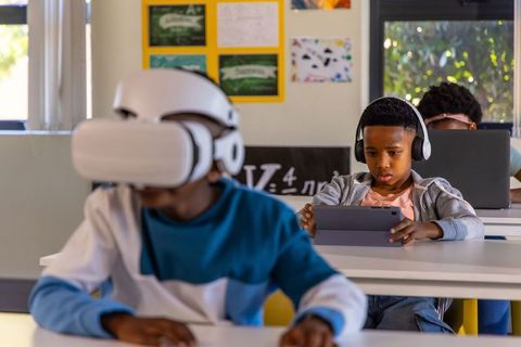 Students using vr headset and tablet engaging with educational technology in classroom