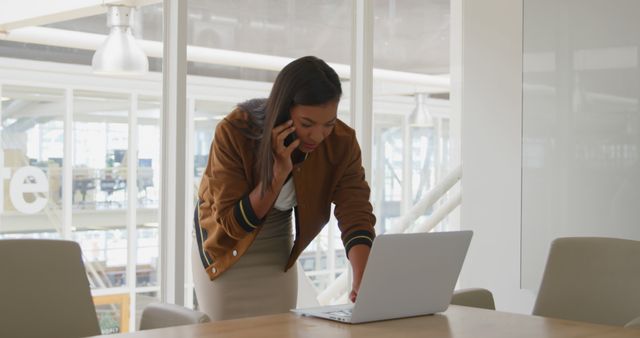 Businesswoman Talking on Phone while Working on Laptop in Modern Office - Download Free Stock Images Pikwizard.com