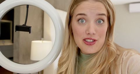 Influencer live streaming in modern bedroom with ring light