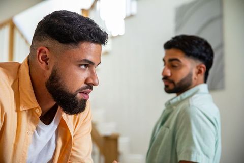 Diverse male friends in serious dialogue near contemporary staircase