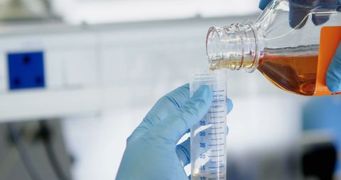 Chemist Pouring Liquid into Graduated Cylinder