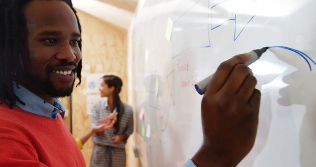 Smiling Professional Man Writing on Whiteboard During Team Meeting - Download Free Stock Images Pikwizard.com