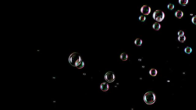 Colorful bubbles captured mid-float against a black background, showcasing their shiny and iridescent properties. Ideal for projects related to cleanliness, simplicity, art, and science. Can be used in advertisements, backgrounds, posters promoting clean products, or visual effects in videos.