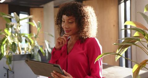 African American Professional Holding Tablet in Modern Office with Greenery
