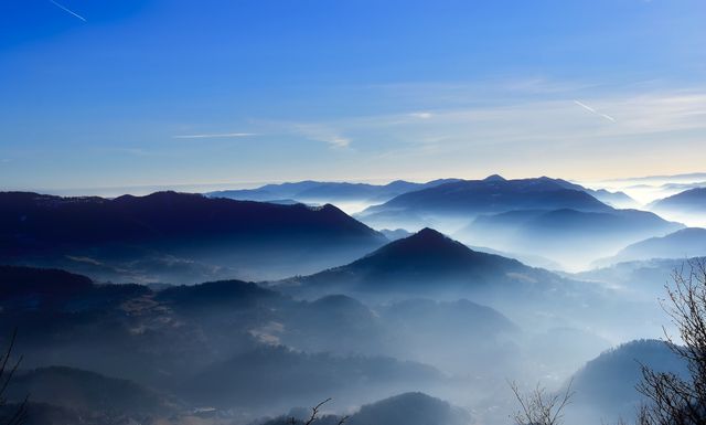 Captured during early morning hours, this mist-covered mountain range creates a serene and tranquil scene. Perfect for backgrounds, travel blogs, and nature-themed presentations, it evokes a sense of calm and wonder with its layered silhouettes and soft blue hues expanding towards the horizon.