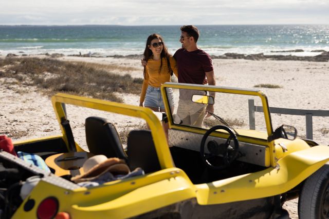 Happy couple walking towards a yellow beach buggy on a sunny beach. Ideal for themes of romance, summer vacations, road trips, and outdoor adventures. Perfect for travel blogs, holiday promotions, and lifestyle advertisements.
