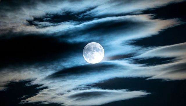 Full Moon Casting Silver Light Through Wispy Clouds Over Dramatic Night Sky