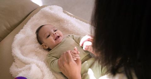 Mother Holding Infant Hand While Laughing