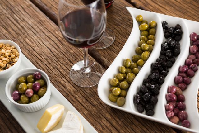 Close-up of marinated olives with glasses of wine on table