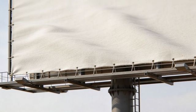 Blank beige billboard canvas hanging on industrial metal frame with catwalk and ladder