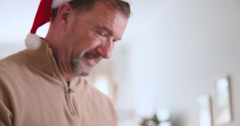 Joyful middle-aged man in santa hat enjoying holiday moments at home