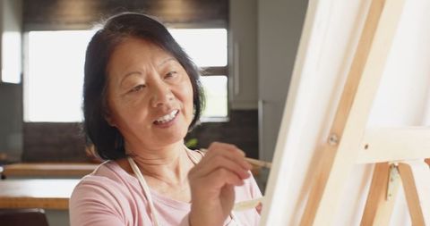 Senior Woman Painting at Easel in Home Kitchen