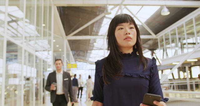 Businesswoman Walking in Modern Airport Terminal with Smartphone - Download Free Stock Images Pikwizard.com