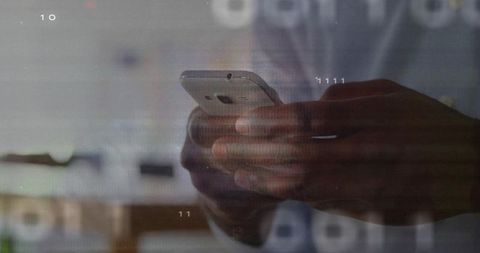 Dark-skinned hands typing on smartphone with digital overlay in modern office workspace