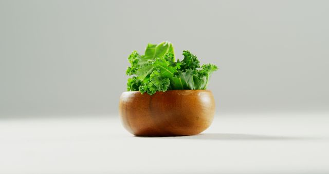 Close up of wooden bowl with green fresh lettuce on white table. Health, diet and food.