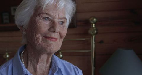 Smiling Elderly Woman Sitting in Bedroom, Contemplative Expression