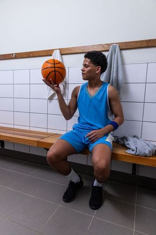 Young basketball player reflecting in locker room with ball