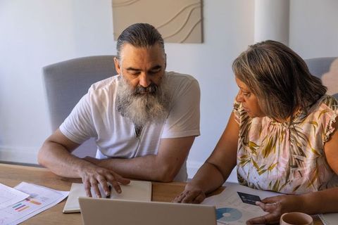 Senior african american woman and man reviewing finances on laptop, budgeting together