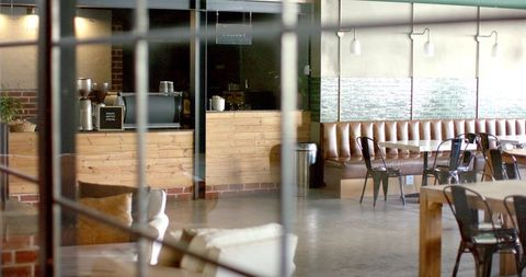 Modern industrial cafe interior featuring wooden coffee counter and leather banquette