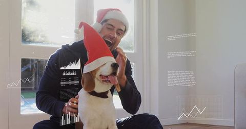 Man wearing santa hat petting beagle by sunlit glass door holiday cozy moment