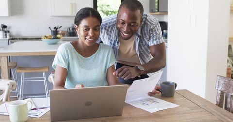 Young Business Couple Managing Budget with Laptop in Modern Kitchen