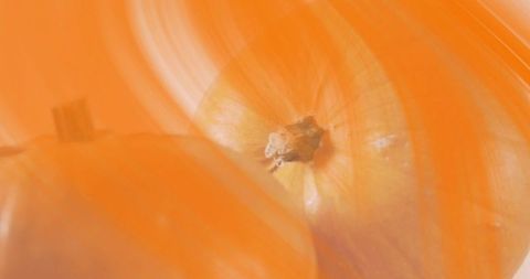 Macro yellow onion with papery skin and root end in warm orange abstract blur