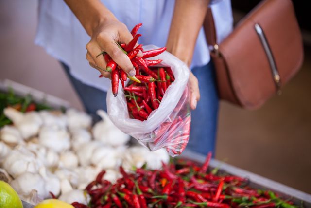 Mid section of woman buying red chilies in supermarket