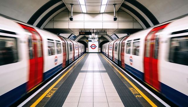 Framing central walkway showing symmetrical london underground platform with moving trains