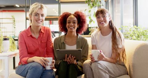 Diverse Female Professionals Relax in Modern Office Lounge