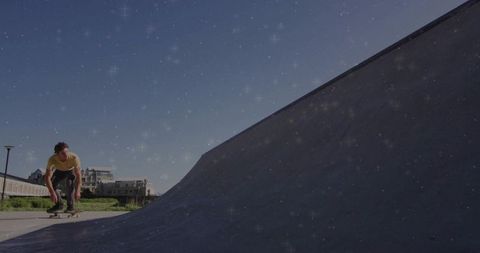 Crouching skateboarder rolling toward quarterpipe at sunny coastal skatepark