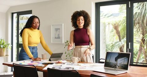 Diverse women collaborating on creative design brainstorming in bright home office