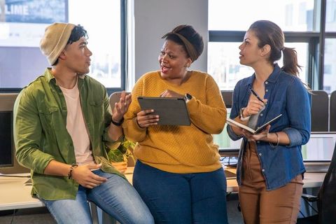 Multiracial Team Collaborating in Modern Open Office Using Tablet and Notebook for Strategy
