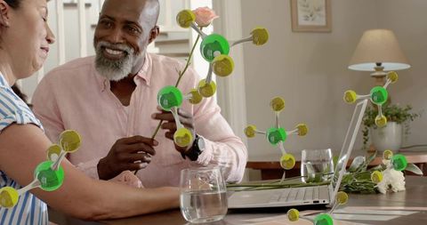 Senior couple sharing rose and smiles while laptop displays floating molecule graphics