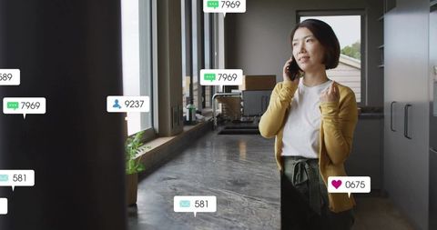 Young woman talking on smartphone in modern kitchen with social notifications and counter