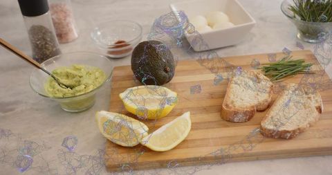 Preparing rustic breakfast board with mashed avocado lemon wedges crusty bread and chives
