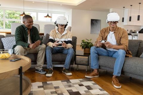Diverse friends playing vr games with wireless controllers in modern living room