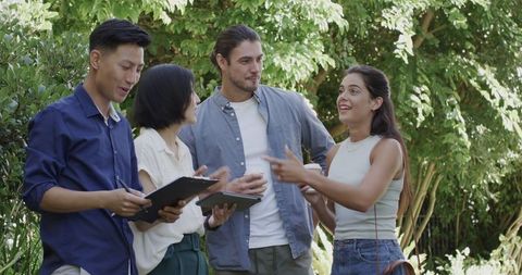 Friends discussing wedding plans outdoors with coffee and clipboard