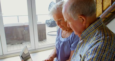 Senior Couple Engaging with Laptop in Bright Living Room