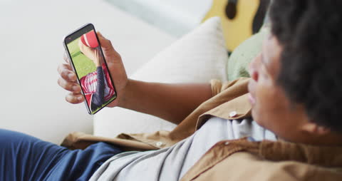 Man Watching Soccer Game on Smartphone, Enjoying in Comfort at Home
