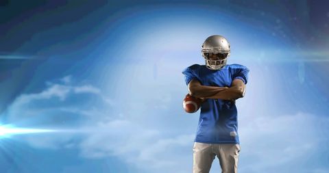 American Football Player Holding Ball Against Blue Sky Backdrop