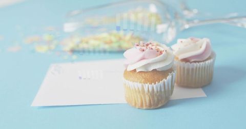 Pastel pink swirl cupcakes on blue background with sprinkles and blank card