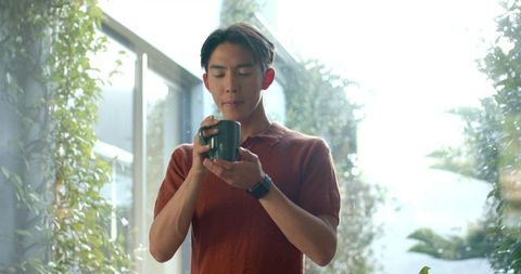 Young man enjoying coffee in modern indoor garden