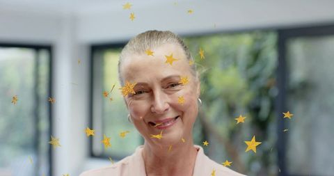 Smiling mature woman in pink blouse and hoop earrings, gold star overlay, serene portrait