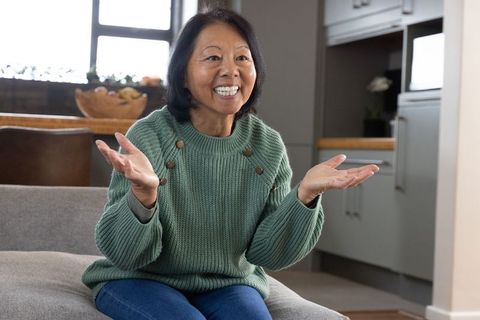 Asian Woman in Green Sweater Having Conversation on Sofa