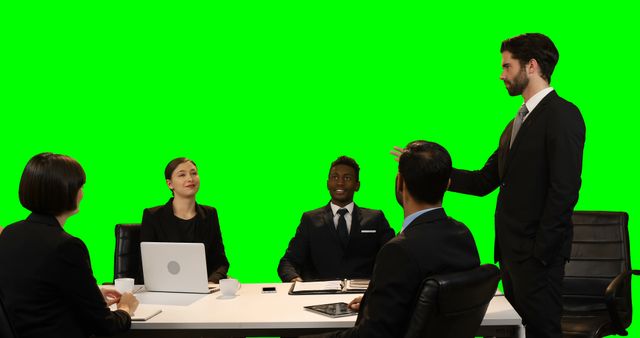 Businessman touching invisible screen during meeting against green screen