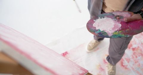 Indian male painter holding palette painting pink abstract canvas overhead studio view