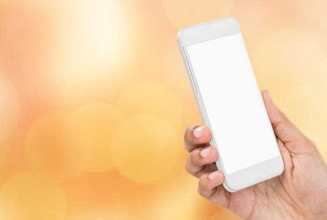Hand holding smartphone with blank screen against orange background, ideal for showcasing mobile apps, websites or technology-related services. Perfect for advertisements, social media campaigns, and tech demonstrations.