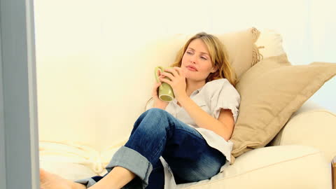Relaxed Woman Daydreaming on Comfortable Couch with Coffee