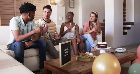 Friends Relaxing at Indoor Gathered Celebration with Drinks and Snacks
