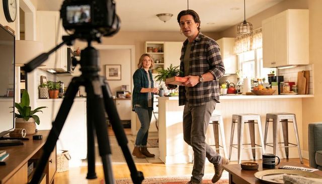 Couple Filming Home Vlog on Kitchen Island Holding Potted Plant and Product Box